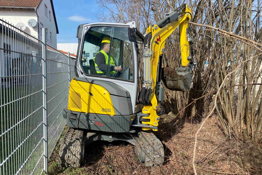 Wacker Neuson Zero Tail bager rad u skučenom prostoru uz zid.