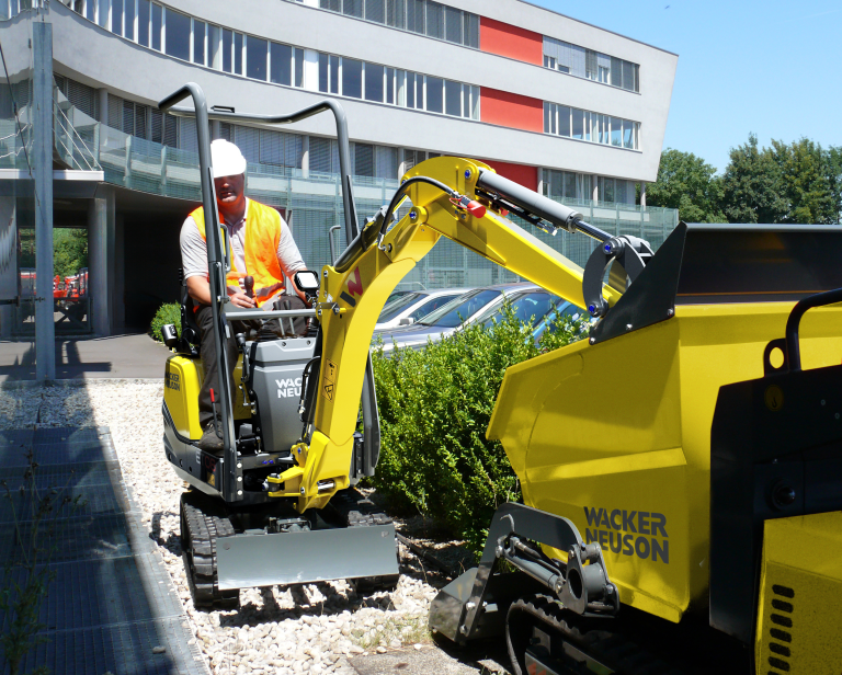 Mini bager gusjeničar na kolniku.